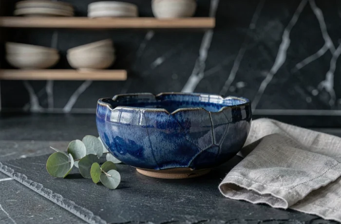 Bol en céramique artisanale émaillée bleu océan sur plan de travail en ardoise, tendance vaisselle fait-main